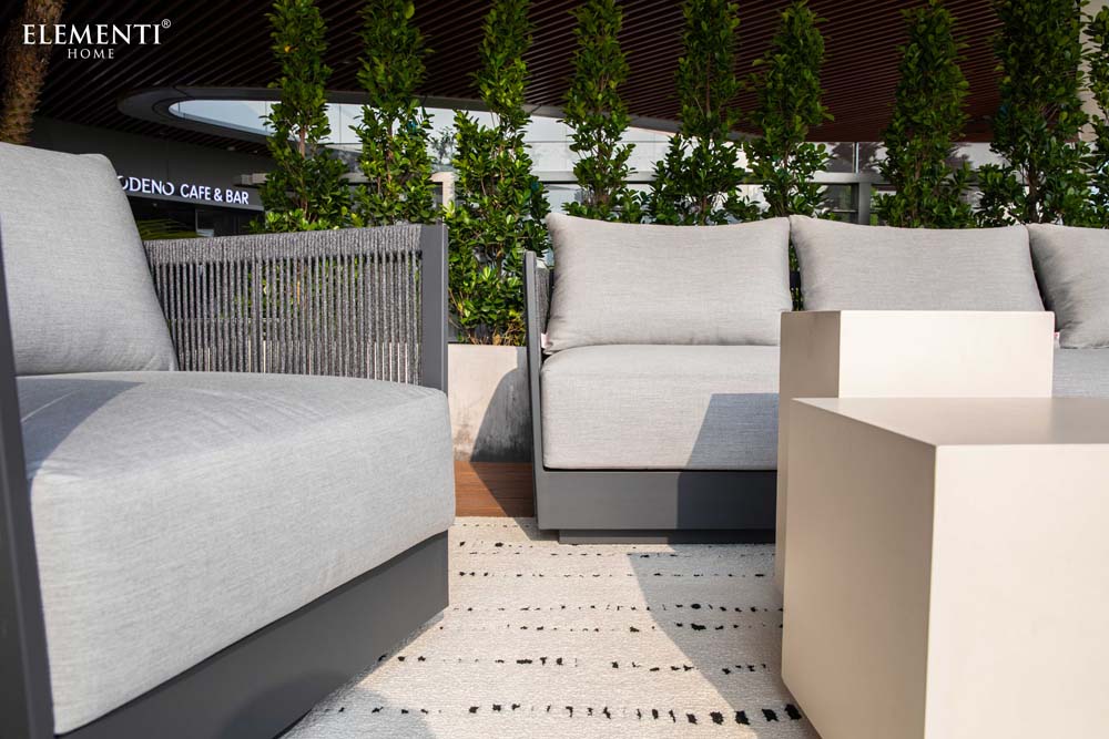 Detailed close-up of the Capri Collection outdoor sofa and chair by Elementi highlighting plush gray cushions, premium fabric, and contemporary design.