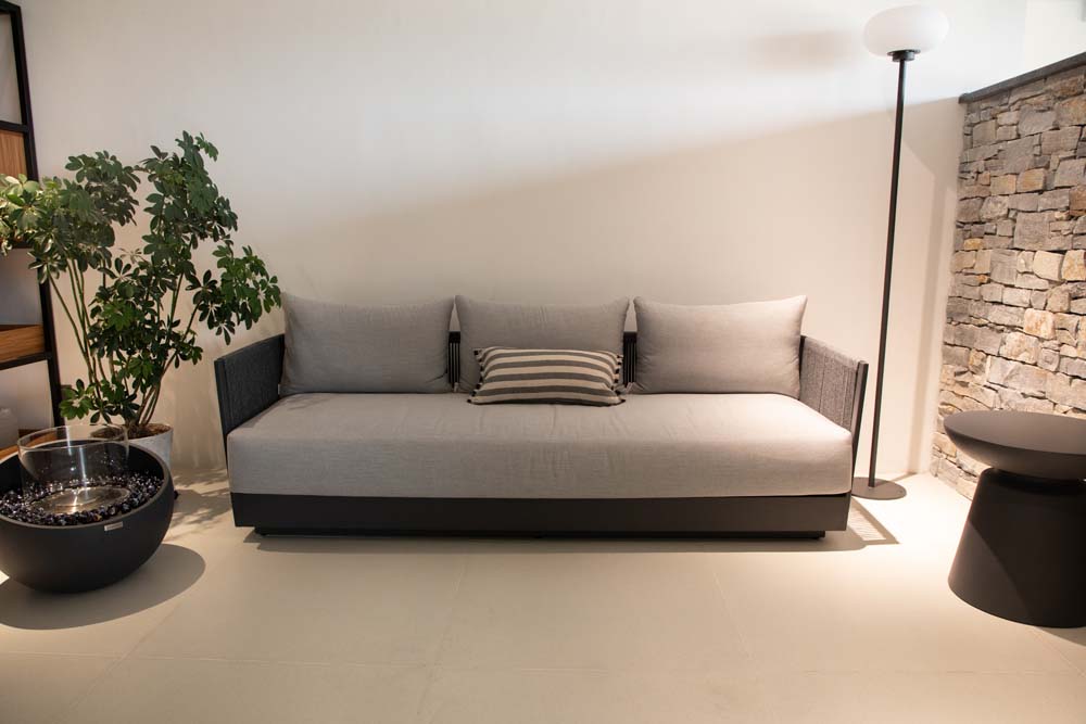 Modern indoor living area showcasing the Elementi Capri Collection sofa complemented by a striped cushion, minimalist decor, and lush green plants.