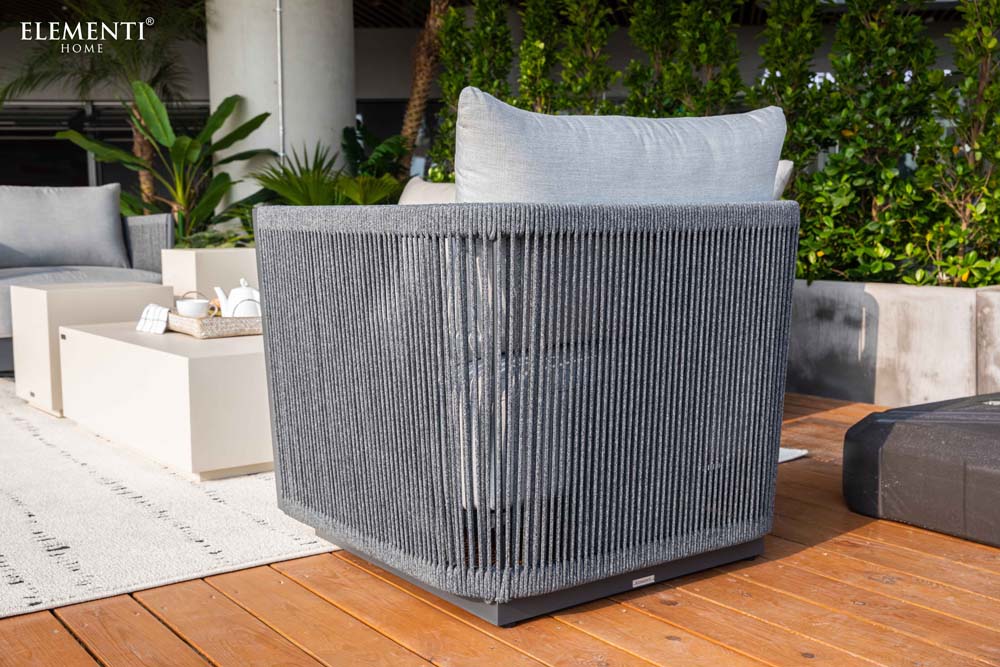 Side perspective of Elementi Capri Collection swivel chair, emphasizing its sophisticated woven rope exterior, plush cushions, and sturdy gray frame.