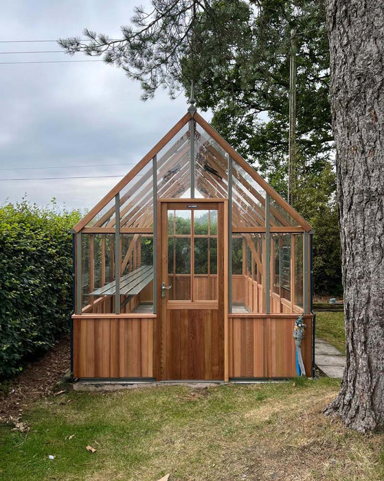 Alton Cedar Structure Cheltenham Greenhouse under tall trees with a shaded garden.