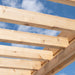 Close-up view looking up through the cedar slat roof of the Urban Escape Pergola against a blue sky