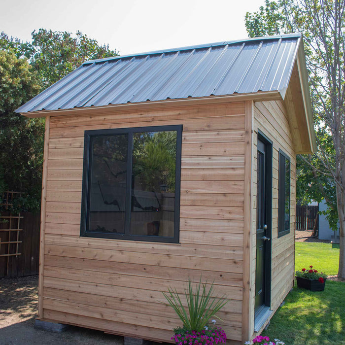 Cedar Saltbox Studio Shed 12x8 shown from a side angle, highlighting its sloped roof and wood-paneled exterior.