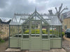 A spacious interior view of the Alton Cedar Structure Durham Greenhouse, showcasing its wooden frame and bright, airy atmosphere.