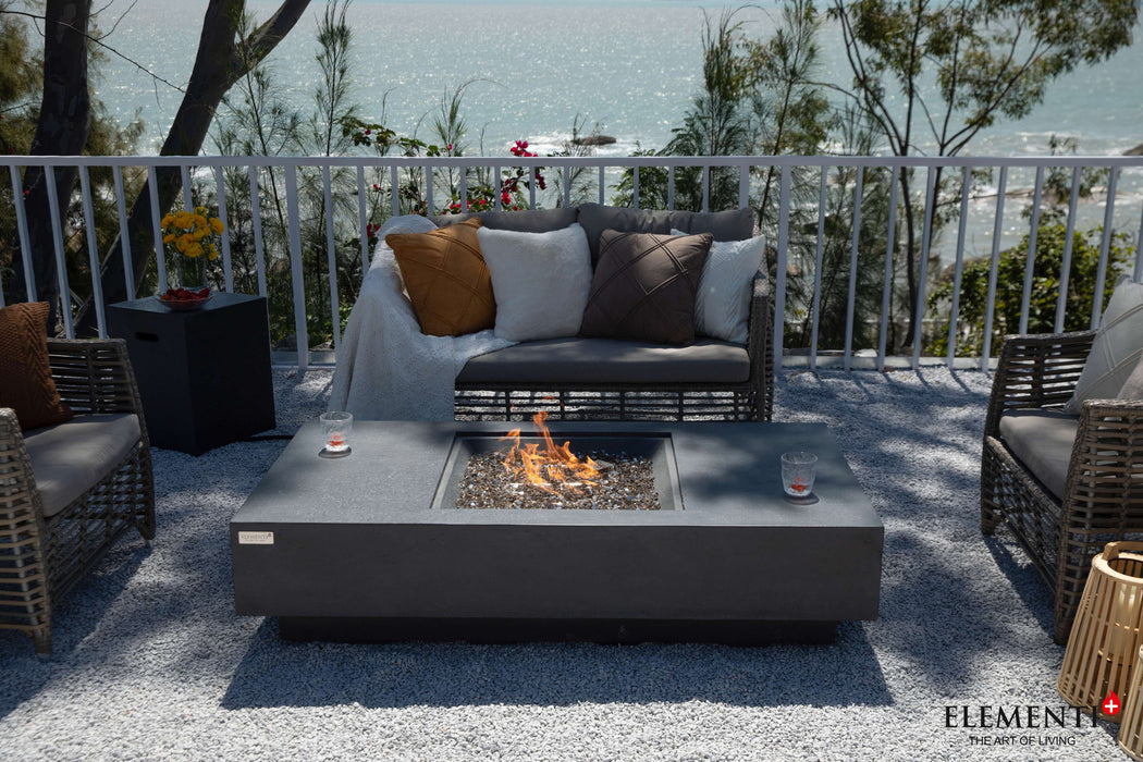 A charming patio with the Elementi Cannes Fire Table at its center, surrounded by elegant wicker furniture for outdoor enjoyment