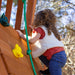 A child climbing on the rock wall of the wooden swing set