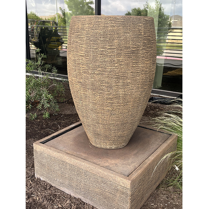 Cigar Outdoor Water Fountain with tall textured vase design on square basin, modern outdoor water feature for garden or patio landscaping.