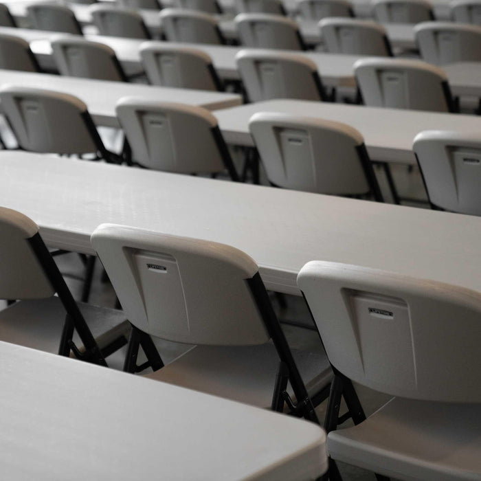 Rows of Lifetime 4-Pack Classic Folding Chairs in putty arranged with rectangular tables for training or classroom use