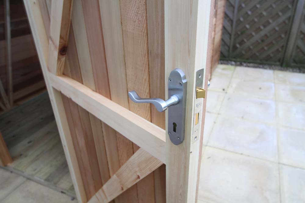 Detailed view of the handle on the wooden door of the Alton Cedar Fusion Greenhouse. 