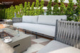 Close-up of a luxurious Elementi Milano Collection outdoor sofa, highlighting its sleek design, plush cushions, and durable grey fabric.