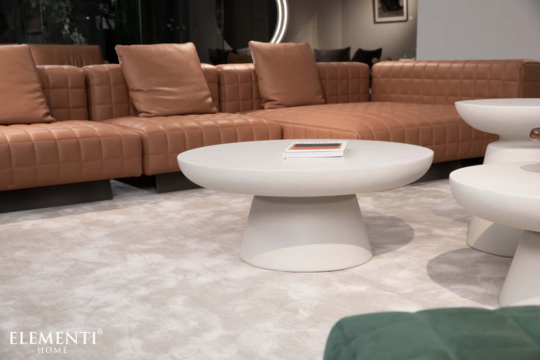 Close-up of Elementi Kylix Series small coffee table in cream white, paired with a brown leather sofa for a modern living room look.