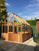 Completed frame structure of the Alton Cedar Structure Cheltenham Victorian Greenhouse in a garden setting.