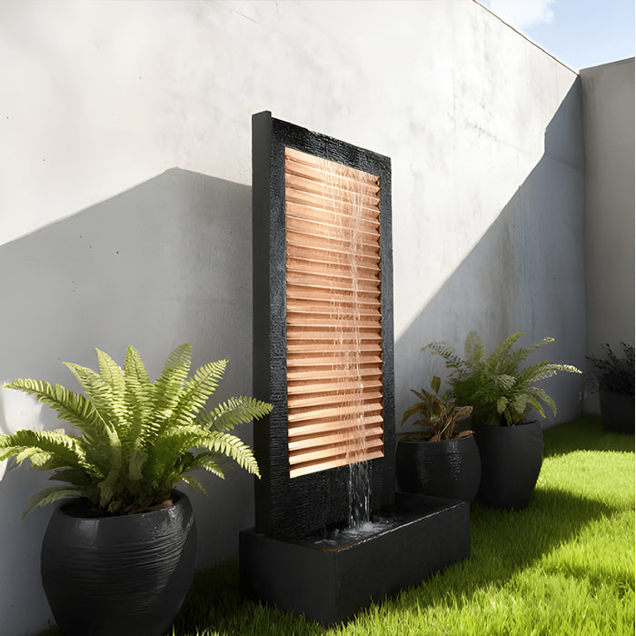 Contemporary backyard water fountain with copper slat design and dark frame, styled with potted plants on green lawn.