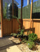 Corner view inside the Alton Cedar Structure Cheltenham Victorian Greenhouse with plants and gravel flooring.