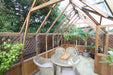 Cosy interior layout of the Alton Cambridge Cedar Greenhouse featuring potted plants and a glass dining table.