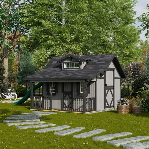 Little Cottage Co. The Craftsman Playhouse in gray with black trim, front porch railing, transom dormer window, and lush backyard setting.