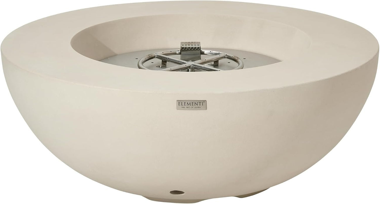 Three-quarter angle view of a round cream white concrete fire bowl revealing the stainless steel burner ring nestled in reddish-brown lava rock; the Elementi Lunar Bowl Fire Table's engraved logo badge sits on the sloped front of the base.