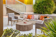 Outdoor setting featuring the Elementi Daintree red wood large coffee table, wicker chairs, and cozy cushions.