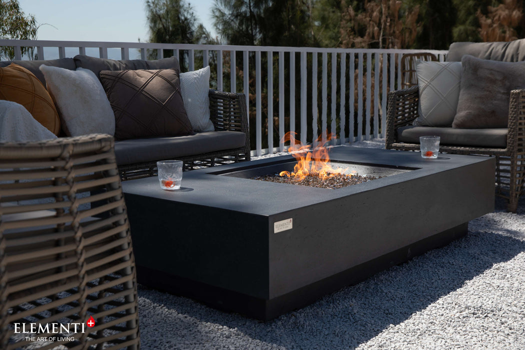  A dark grey Cannes fire pit on a patio, complemented by wicker chairs, perfect for outdoor gatherings and relaxation