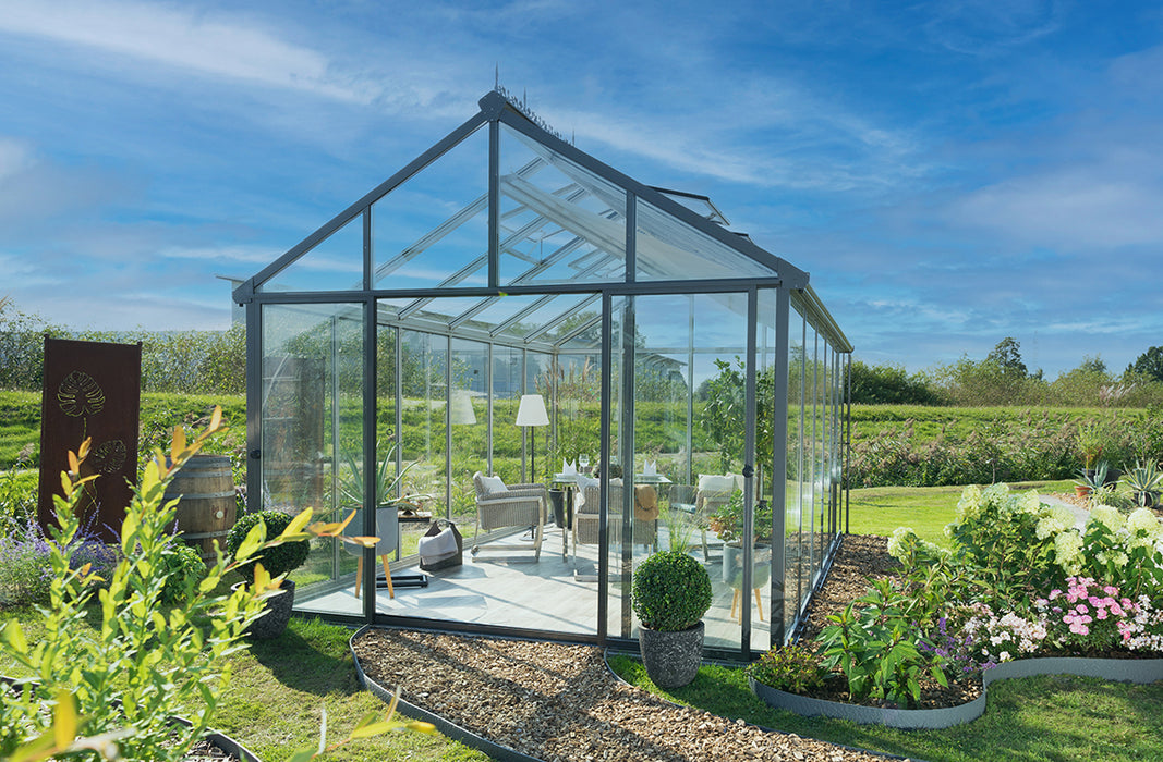 An elegant exaco glass greenhouse constructed with transparent glass panels and a sturdy frame, bathed in daylight.