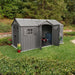 Lifetime 15x8 ft. dual entry storage shed installed on a hillside backyard with open door and mower visible inside.