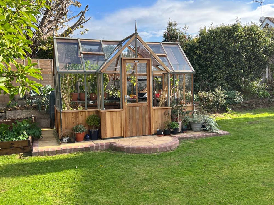 A side-angle overview of the Alton Cedar Structure Durham Greenhouse 7x12, capturing its clean lines and functional layout.