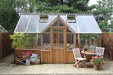 Elegant exterior view of the Alton Cambridge Cedar Greenhouse with patio furniture and potted plants.