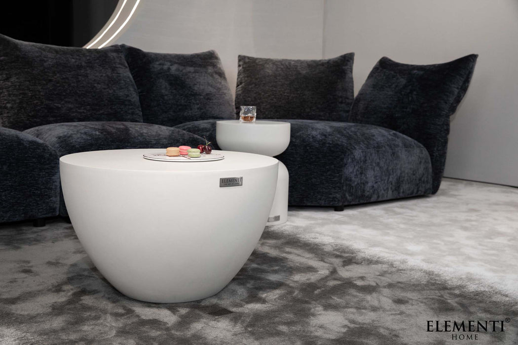 Small Elementi Chronos Series coffee table in cream white, set in a modern living room with a dark plush sofa.