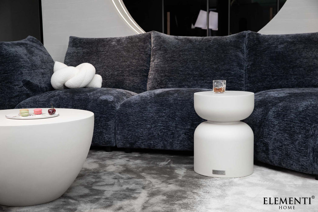 Elementi Chronos Series small side table in cream white, featured in a modern room setting alongside a sofa.