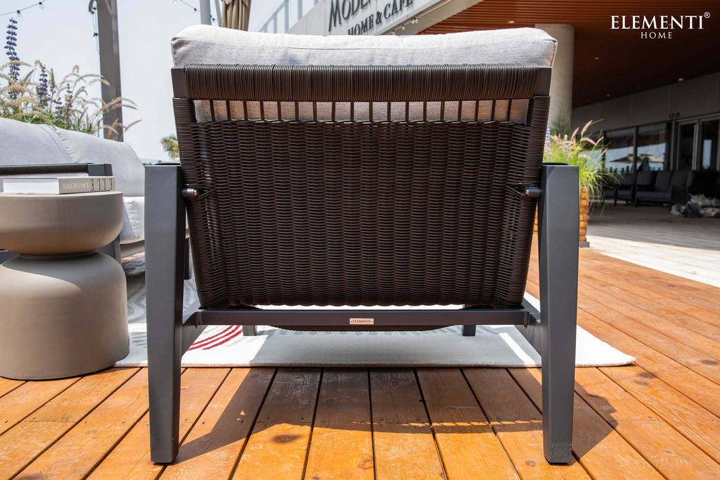 The back of a woven outdoor chair from the Elementi Laguna Collection, highlighting its durable woven back and sturdy frame.