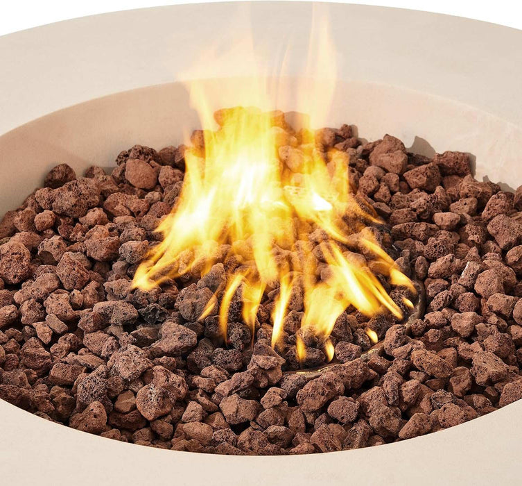 Extreme macro close-up of bright orange and yellow flames rising through reddish-brown lava rocks inside the cream white concrete basin of the Elementi Lunar Bowl Fire Table, showcasing the smokeless burner flame pattern and volcanic rock media in detail.