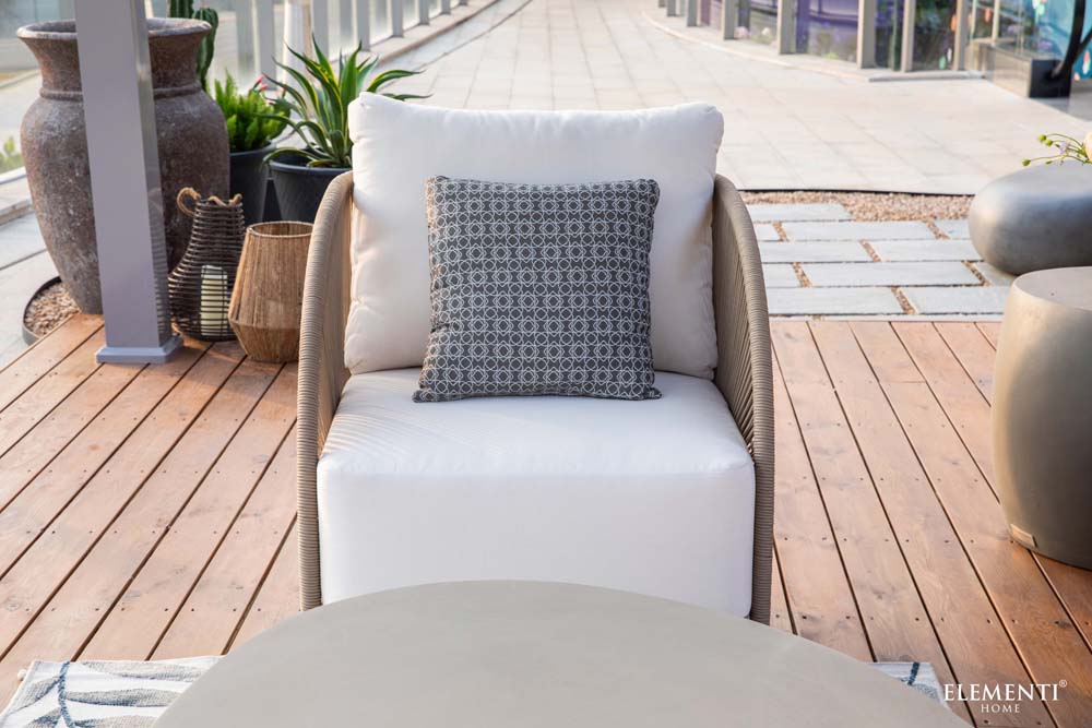 Front view of Malibu Collection outdoor chair by Elementi with clean white cushions and rounded arms, situated on a modern wooden deck.