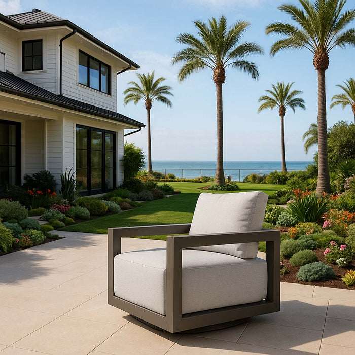 Elementi Newport Collection outdoor armchair on a patio overlooking the ocean, surrounded by lush landscaping and palm trees.