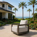Elementi Newport Collection outdoor armchair on a patio overlooking the ocean, surrounded by lush landscaping and palm trees.