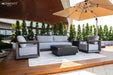 Elementi Outdoor Furnitures Newport Collection lounge set with a sofa, armchairs, and a coffee table under a large umbrella.