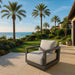 Elementi Outdoor Furnitures Newport Collection armchair on a beautiful patio with a scenic ocean view and vibrant garden.