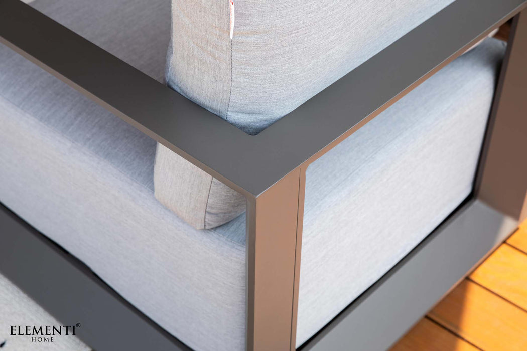 Detailed view of the Elementi Outdoor Furnitures Newport Collection sofa, highlighting its modern grey frame and light cushions.