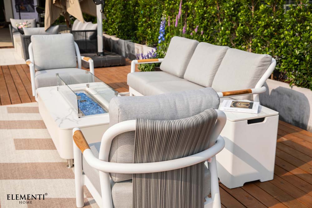A close-up of Elementi Outdoor Furniture's Santorini Collection with a light gray armchair and a modern outdoor fire pit.