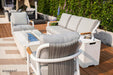 A close-up of Elementi Outdoor Furniture's Santorini Collection with a light gray armchair and a modern outdoor fire pit.