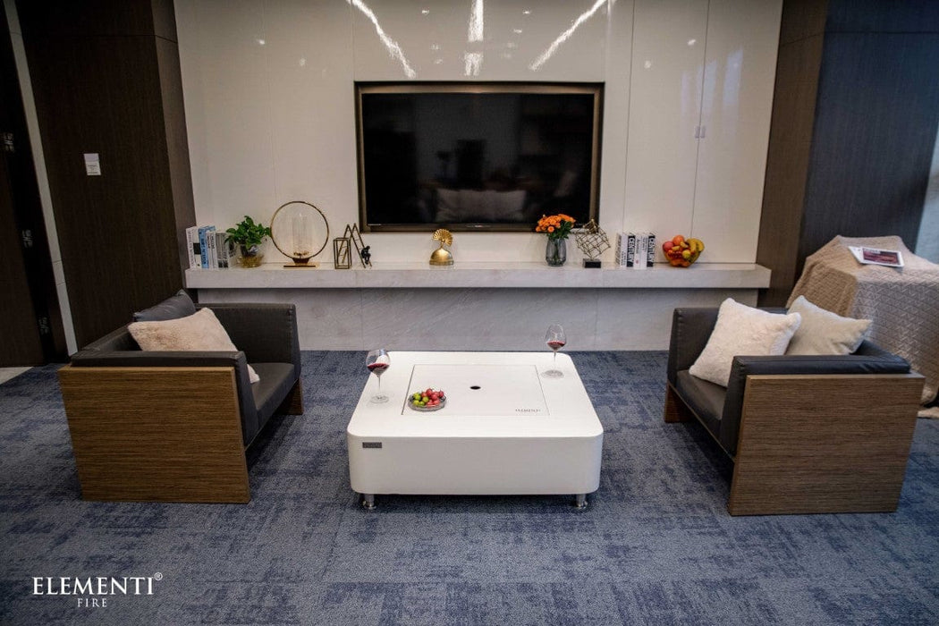 Perth Ethanol Fire Table by Elementi with the lid on, set between armchairs in a cozy lounge area