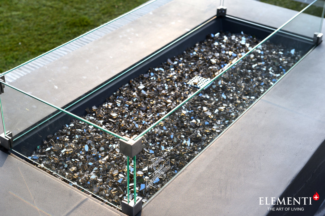 Elementi Plus Rectangular Wind Screen OFG410/415-WS around an outdoor fire pit, surrounded by glass crystals and providing wind protection.