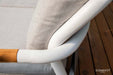 A close-up view of a light gray cushion resting on a curved white frame, part of the Elementi Santorini Collection outdoor furniture.