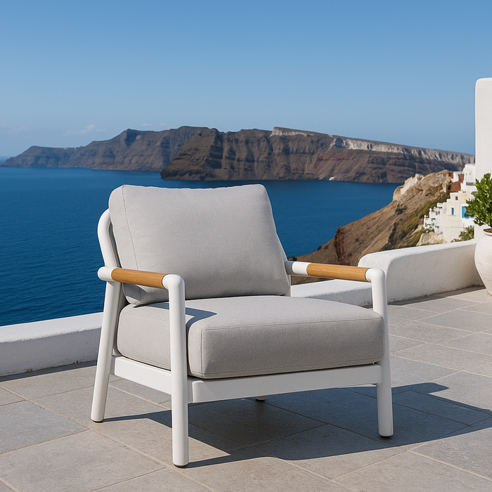 Contemporary lounge chair from Elementi Outdoor Furnitures Santorini Collection with scenic sea cliffs and white stone patio.