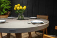 Elementi Verona Dining Table in space grey, close-up shot showing the tabletop surface and a centerpiece of yellow flowers.