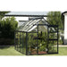 Exaco Janssens Junior Victorian Greenhouse standing in a peaceful yard, with neat hedging and a softly shaded interior.