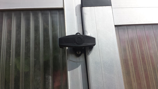 Exaco greenhouse window lock accessory attached to aluminum frame, providing secure closure for panels and added protection against wind.