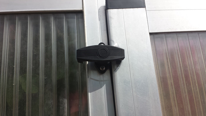 Exaco greenhouse window lock accessory attached to aluminum frame, providing secure closure for panels and added protection against wind.