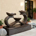 Exaco Infinity fountain in Rust on a patio beside a stucco wall and potted plants.