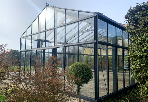 Exaco Janssens Gigant Greenhouse with black aluminum frame and full glass panels, exterior front garden view
