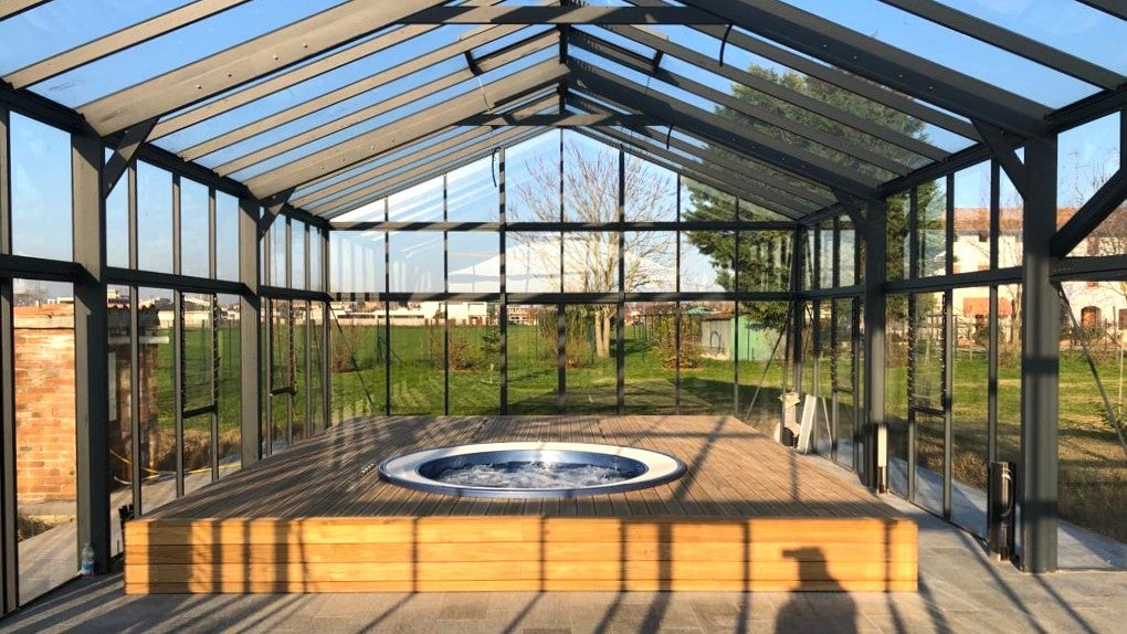 Exaco Janssens Gigant Greenhouse interior with glass walls and central built-in hot tub on raised wooden platform