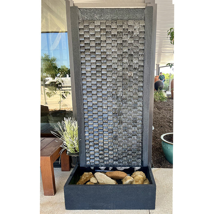 Exaco Laguna Wall Fountain featuring a sleek, tall design with a textured water wall and a stone-filled base, creating a stylish water feature for any outdoor space.